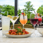 A patio table full of of cocktails and wines for Happy Hour